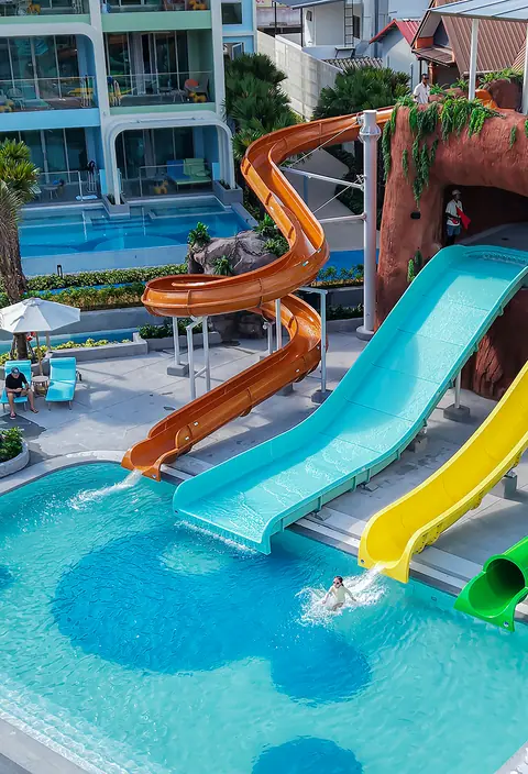 Colourful water slides spiralling down into a resort pool